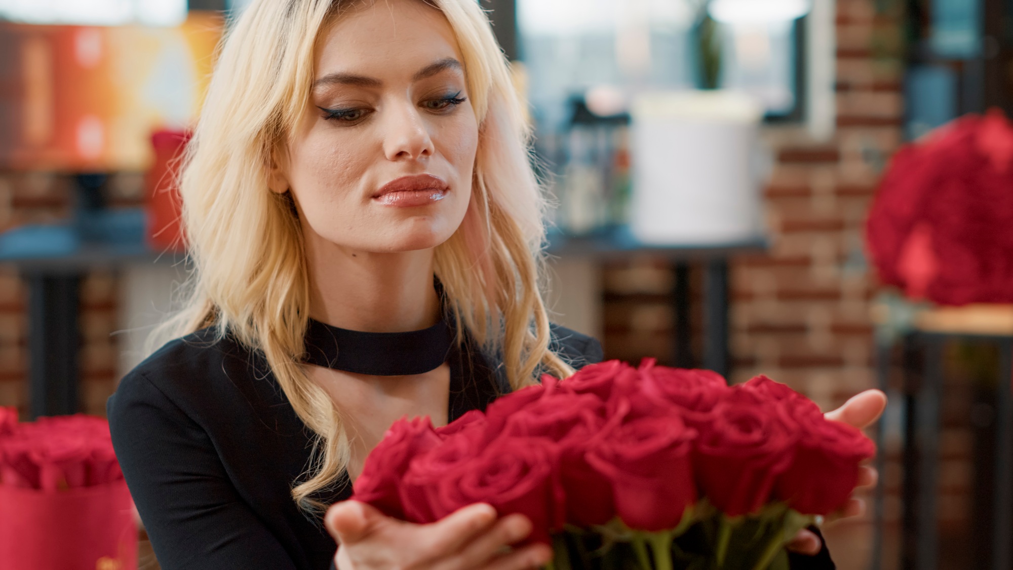 Portrait of romantic beautiful woman smiling and smelling roses feeling in love admiring luxury gift